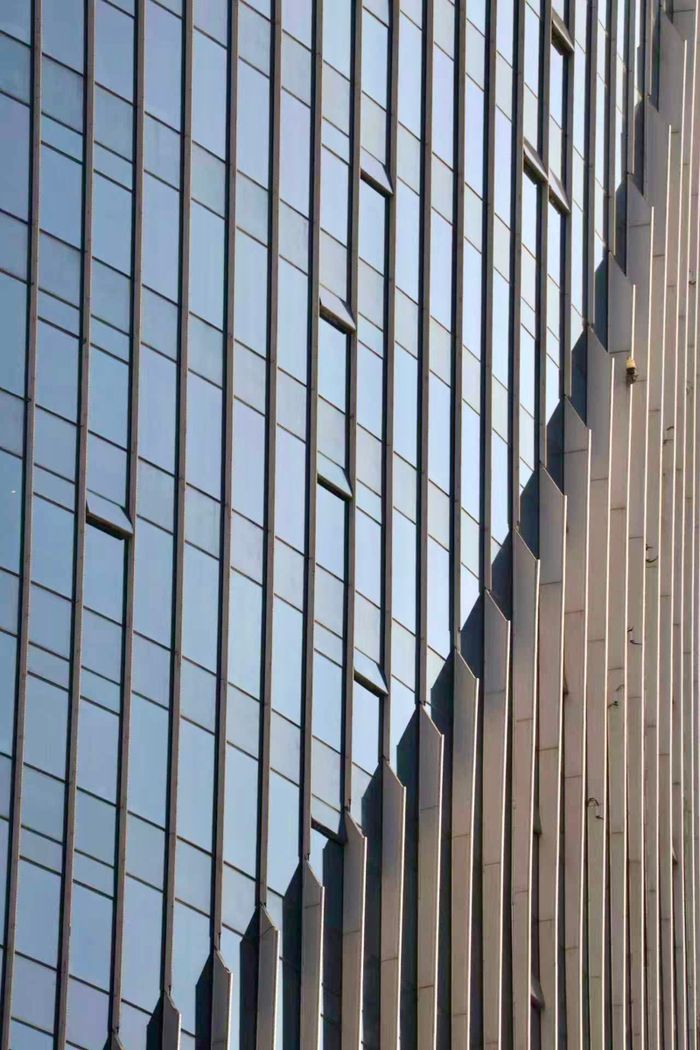 our-story Close-up of a modern skyscraper facade featuring vertical lines and geometric shapes.
